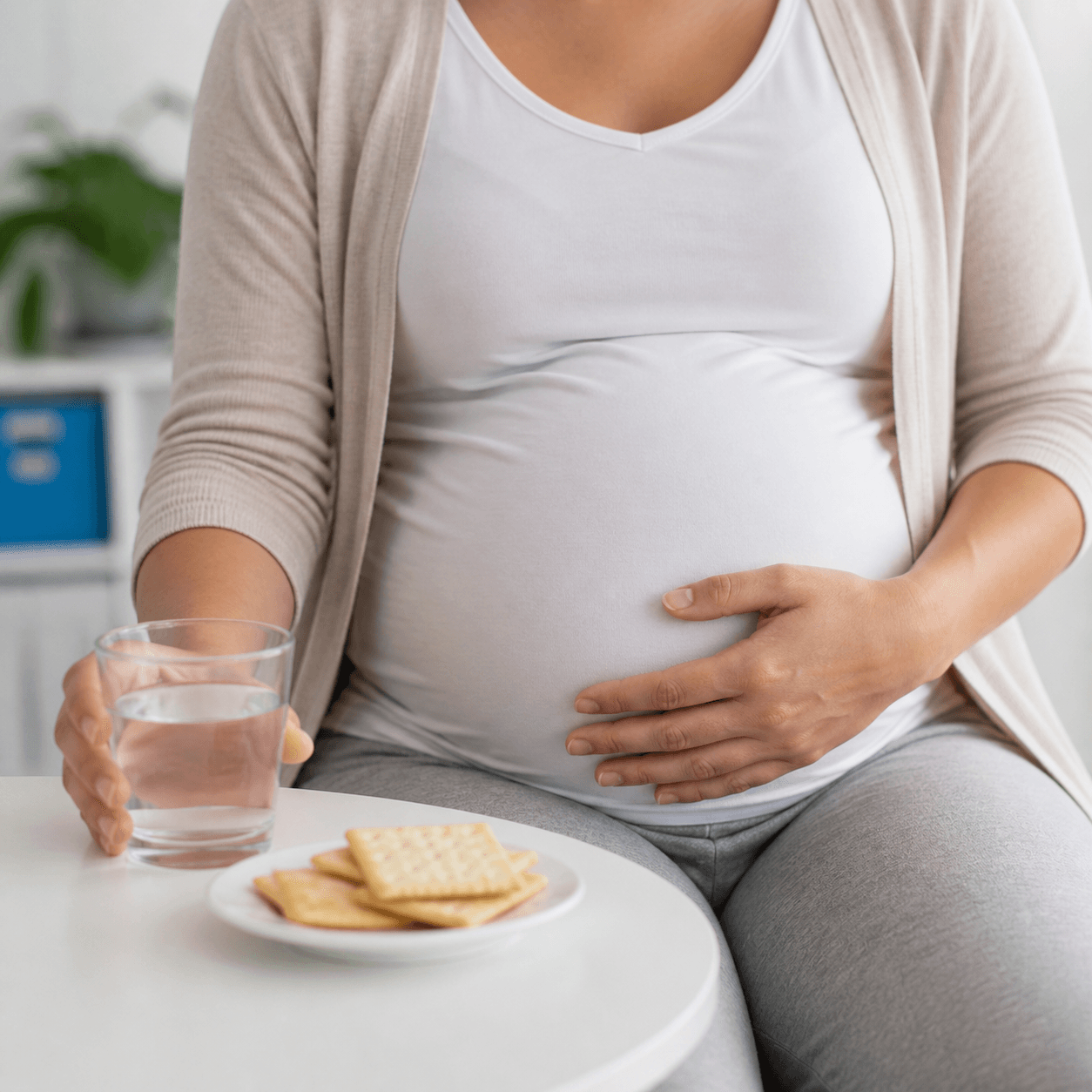 Generated clinical photo showing a pregnant person with nausea using crackers and water